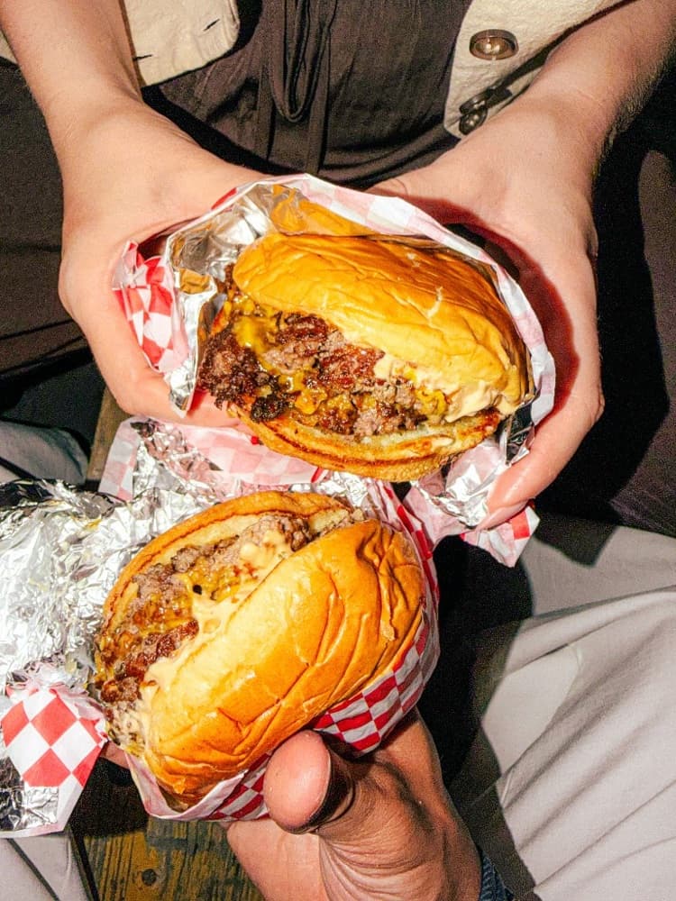 Hands assembling a burger on a wooden board