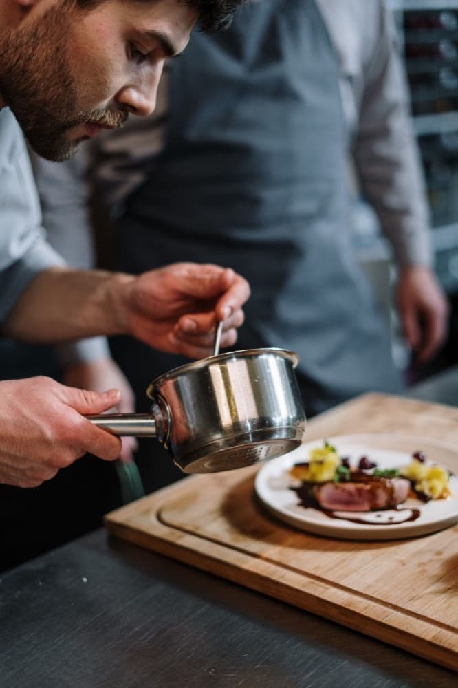 A chef plating a dish in a restaurant kitchen